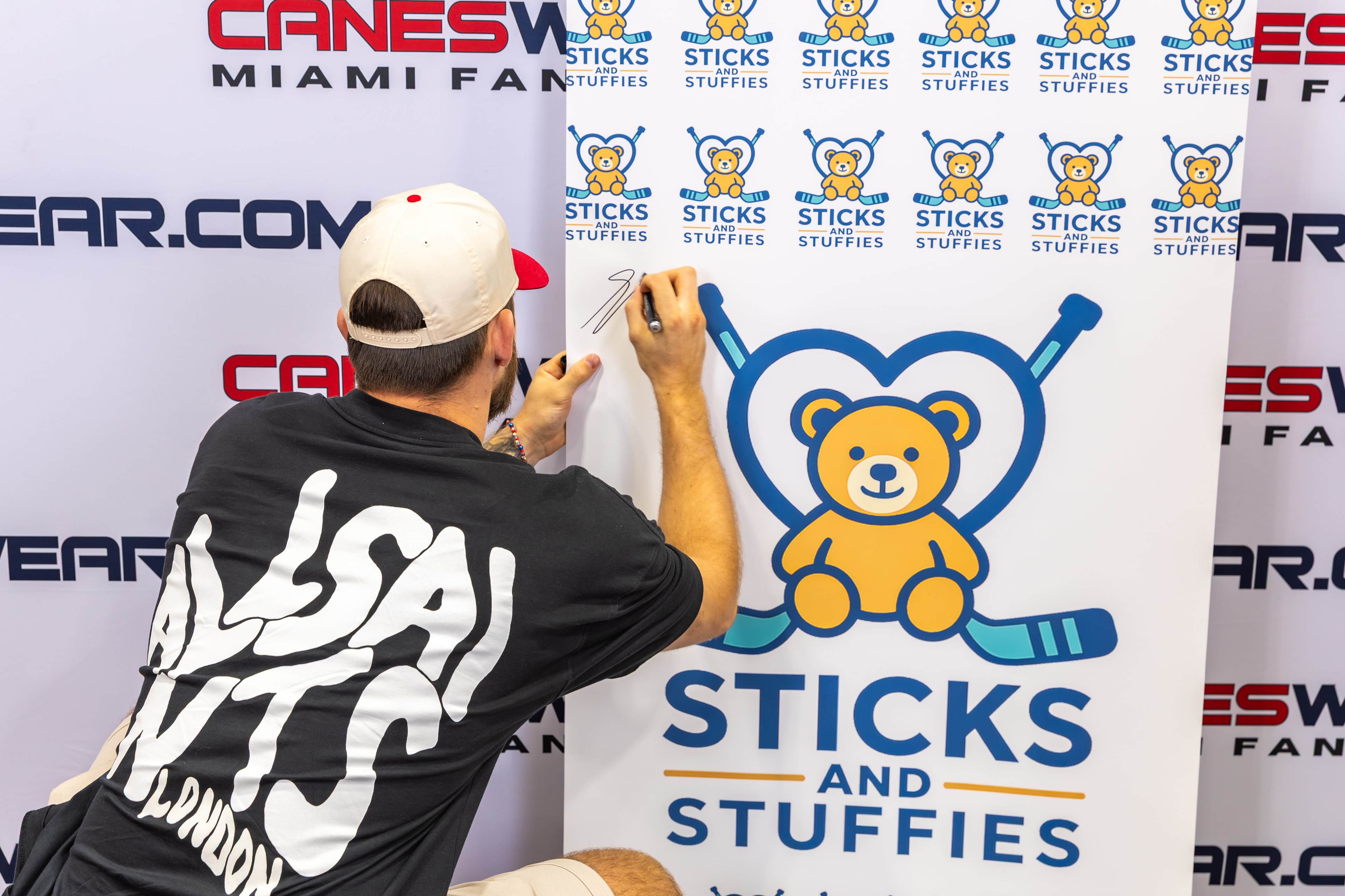 Florida Panthers player A.J. Greer signing the Sticks and Stuffies banner at CanesWear